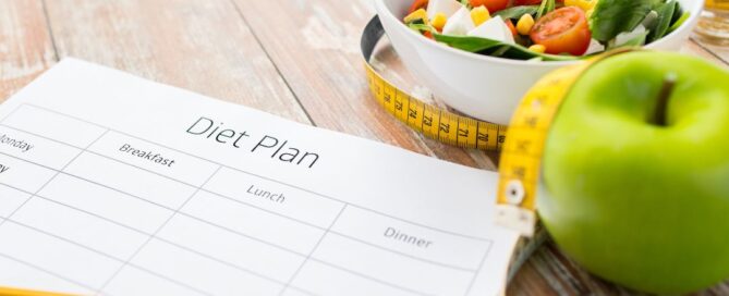 There is an apple and paper and pencil that says diet plan. Also a salad.