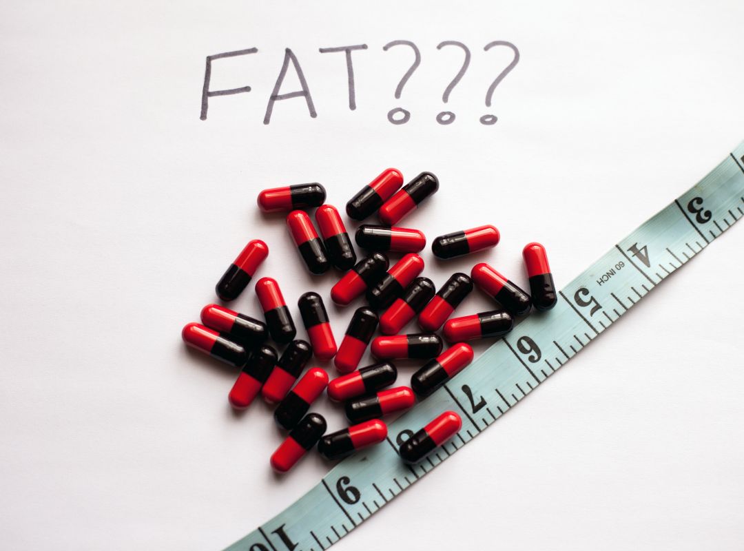 Picture for Key Nutrition blog post. Pictures are red and black capsules, a measuring tape, and the text "Fat???" on a white background.